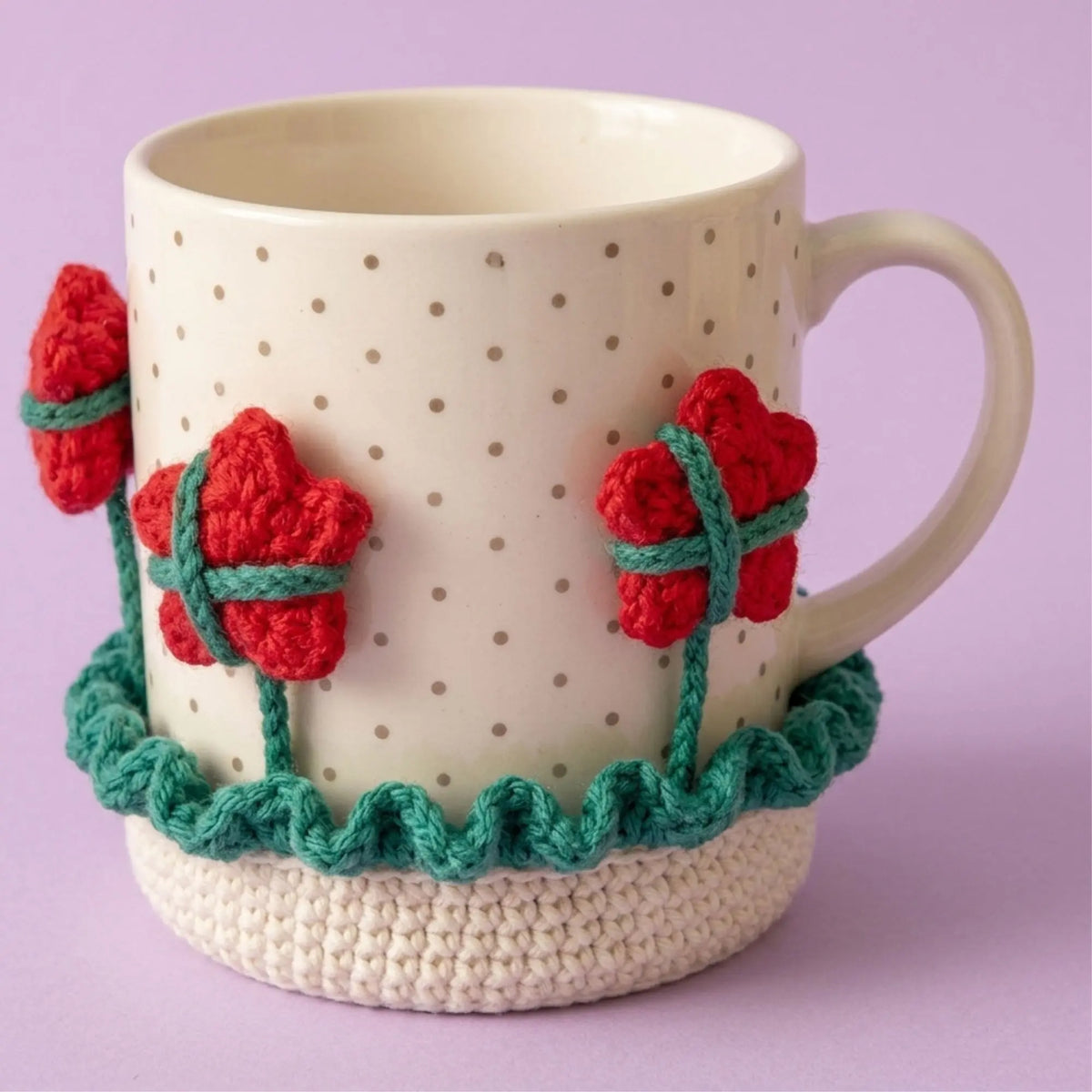 Red flower crochet mug cozy coaster on a polka dot mug