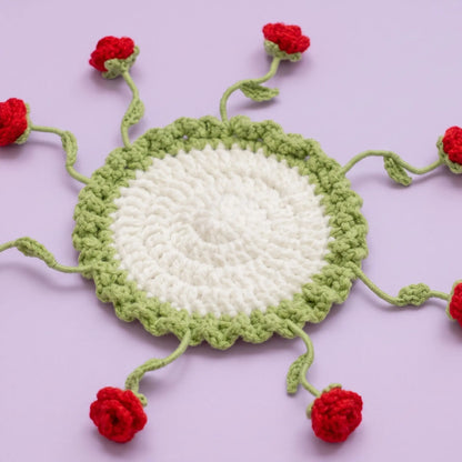 Flat red rose crochet coaster laid out with stems spread around