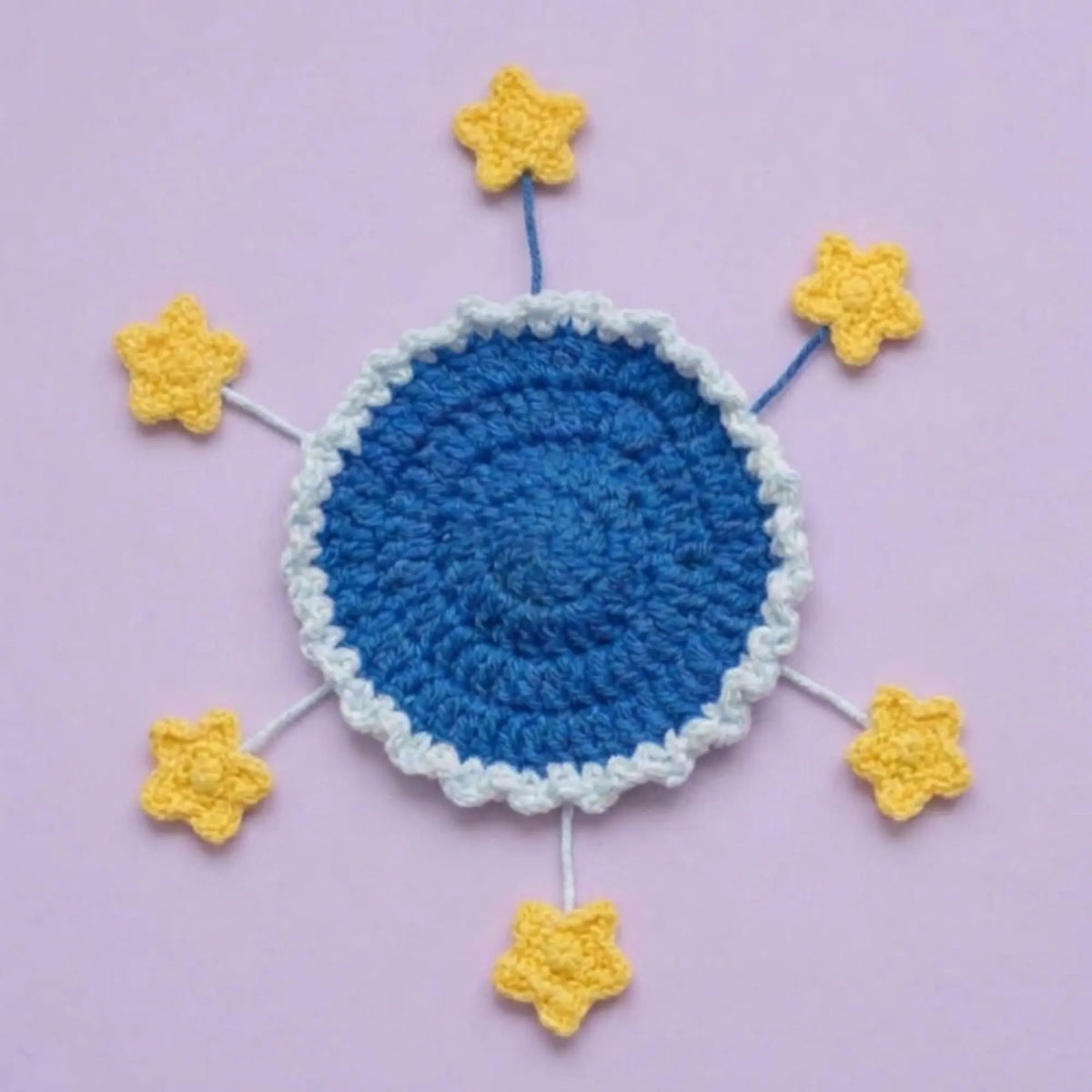 Flat blue crochet coaster with yellow stars on spread-out stems
