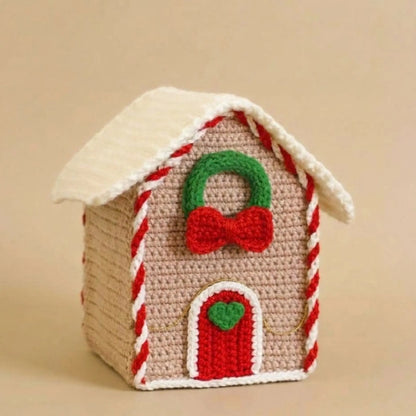 Crochet gingerbread house amigurumi with snowy roof, candy cane trim, wreath and red door
