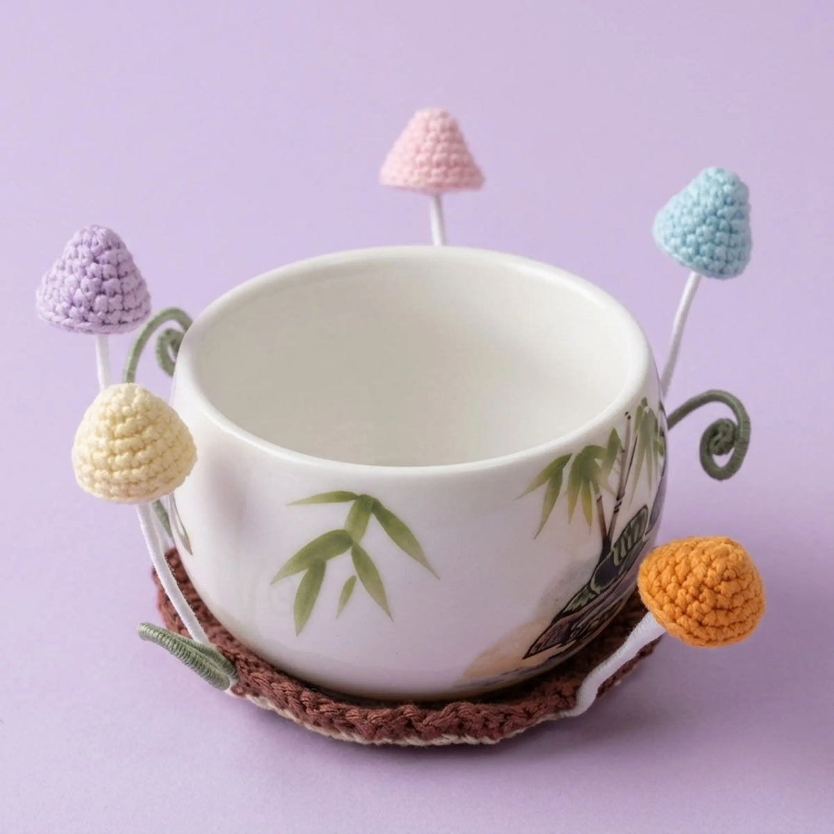 Pastel toadstool mushroom crochet coaster around a white teacup