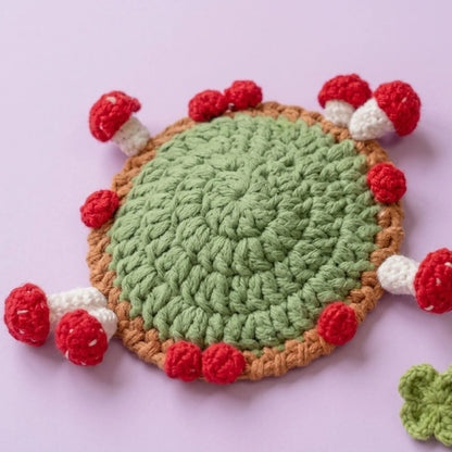 Red berry and mushroom crochet coaster ring on a green base