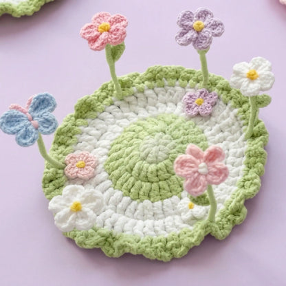 Crochet pop-up garden coaster with pink, purple and blue flowers on wire stems