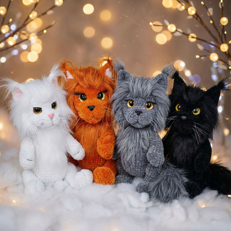Four realistic crochet Maine Coon cat amigurumi dolls in white, orange, grey, and black with fairy lights bokeh background